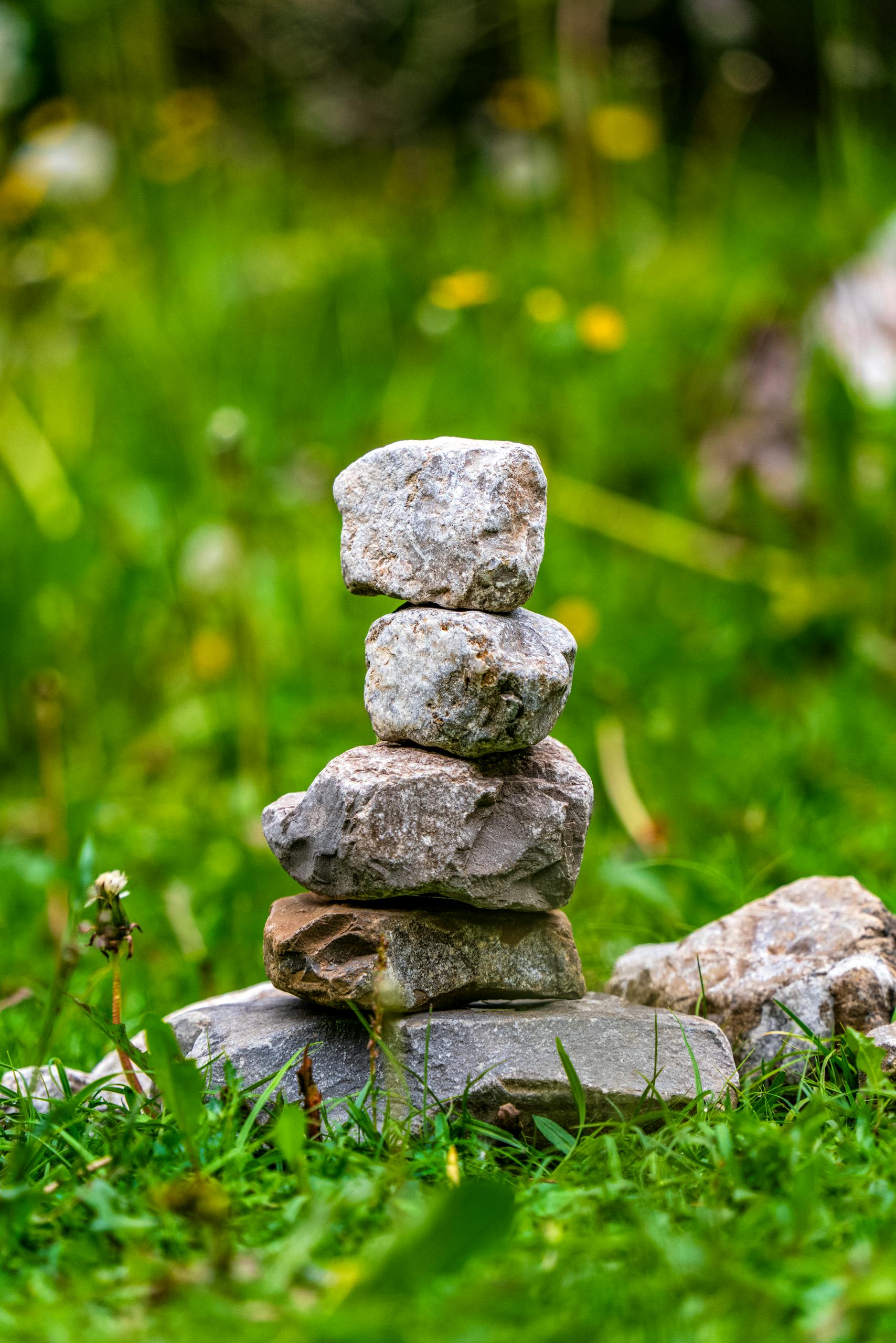 Close-up of balanced stones stacked on green grass, symbolizing harmony and balance.